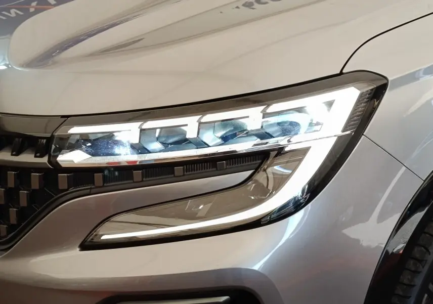 Gros plan sur le phare avant droit allumé du Renault Austral gris clair, soulignant le design LED distinctif.