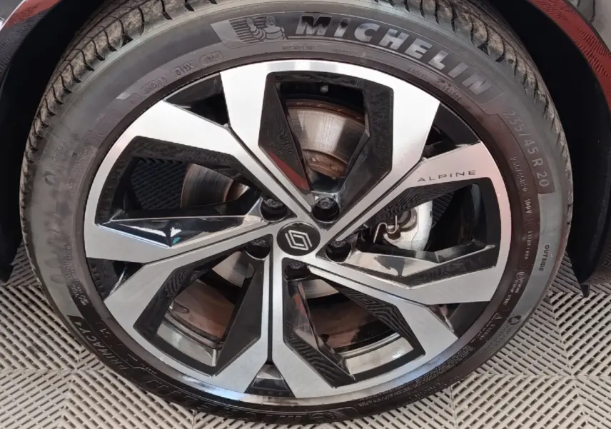 Gros plan sur la jante alu bicolore avec logo Alpine et pneu Michelin du Renault Austral gris clair.