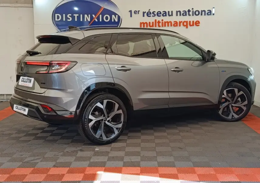 Vue latérale droite du Renault Austral gris clair avec jantes noires et détails Alpine E-Tech, en intérieur showroom.