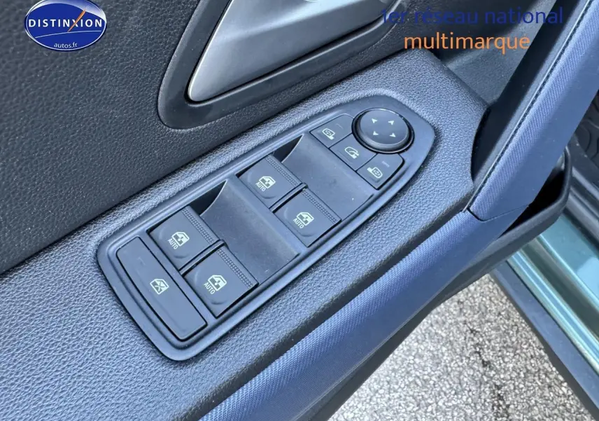 Gros plan sur les commandes des vitres électriques côté conducteur du Dacia Duster vert cèdre 2025, porte ouverte.