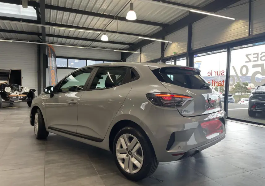 Vue 3/4 arrière droite d'une Renault Clio 1.5 Blue dCi 2025 gris Rafale avec feux LED et jantes alliage en showroom.