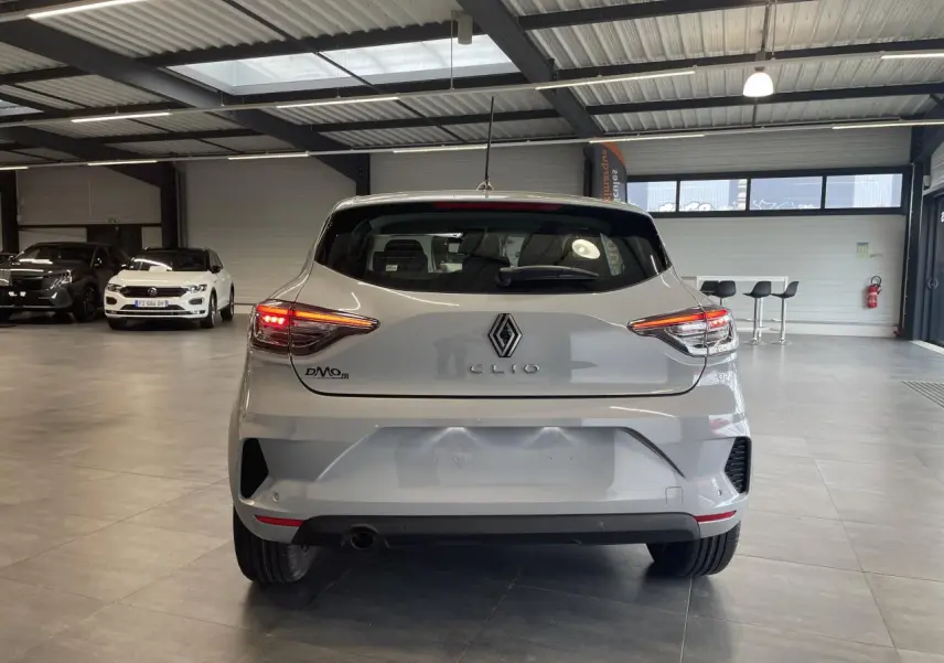 Vue arrière d'une Renault Clio 1.5 Blue dCi 2025 en gris Rafale, avec feux LED allumés dans un showroom.