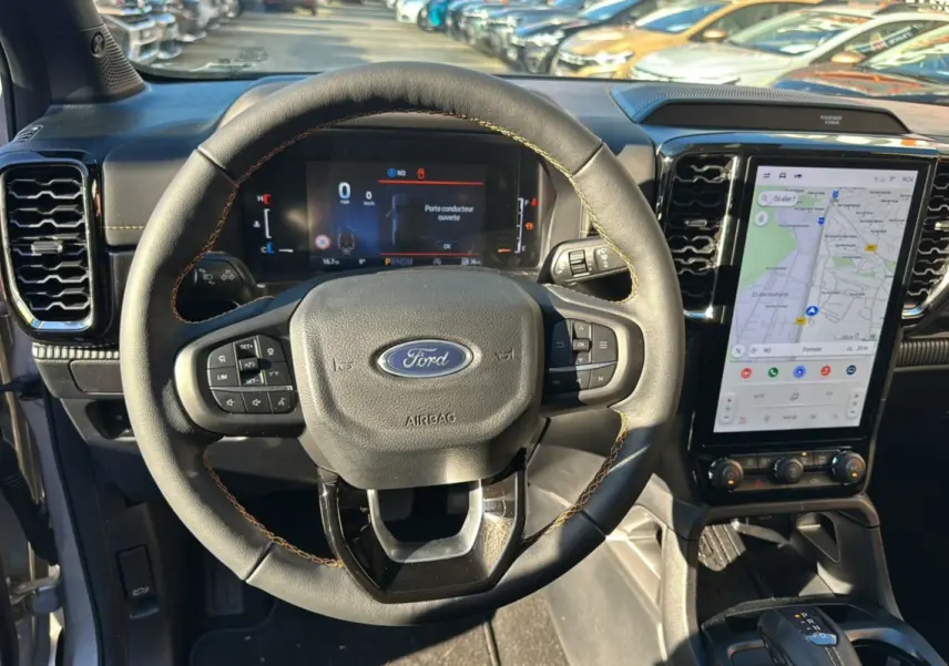 Vue intérieure centrée sur le volant cuir avec coutures marron et écran tactile vertical du Ford Ranger gris iconic 2026.