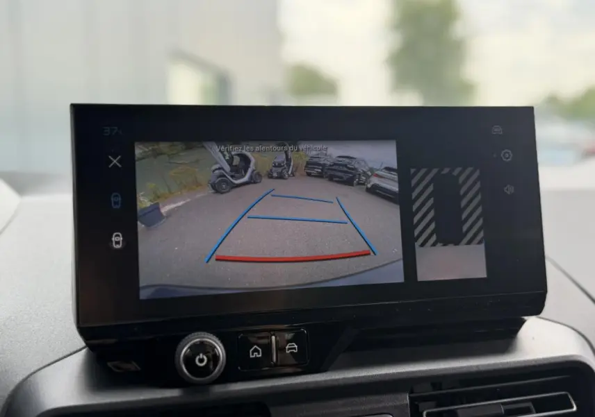 Écran tactile intérieur montrant la caméra de recul du Peugeot Rifter vert Sirkka, vue arrière avec lignes de guidage colorées.