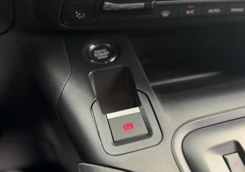Gros plan sur la console centrale du Peugeot Rifter avec bouton frein de stationnement électrique allumé en rouge.