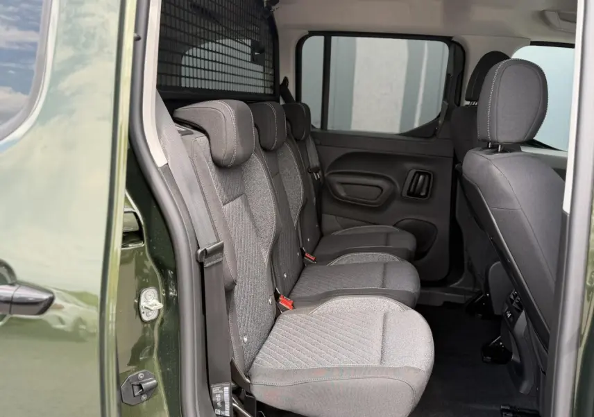 Vue intérieure côté gauche du Peugeot Rifter vert Sirkka montrant les trois sièges individuels arrière en tissu gris.