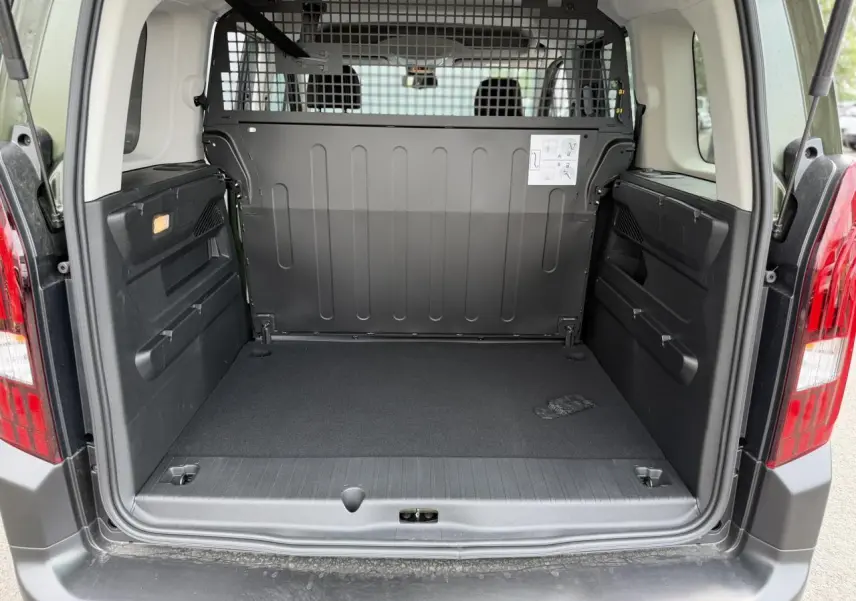 Coffre ouvert vu de l'arrière du Peugeot Rifter vert Sirkka, montrant l'espace de chargement et la grille de séparation.