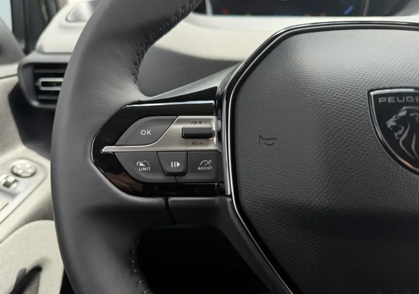 Gros plan sur le volant cuir multifonction du Peugeot Rifter 2026, avec commandes intégrées et logo lion central.
