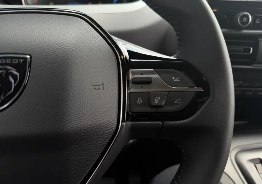 Gros plan sur le volant cuir multifonction du Peugeot Rifter 2026, boutons de commande audio et téléphone visibles.