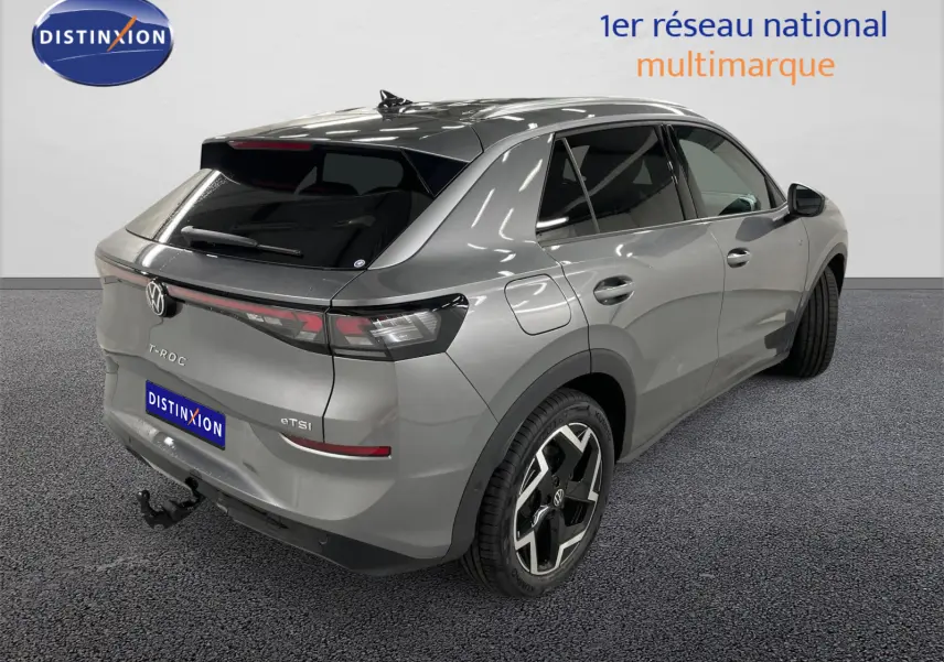 Vue 3/4 arrière droite du Volkswagen T-Roc gris Loup avec attelage escamotable et vitres arrière surteintées.