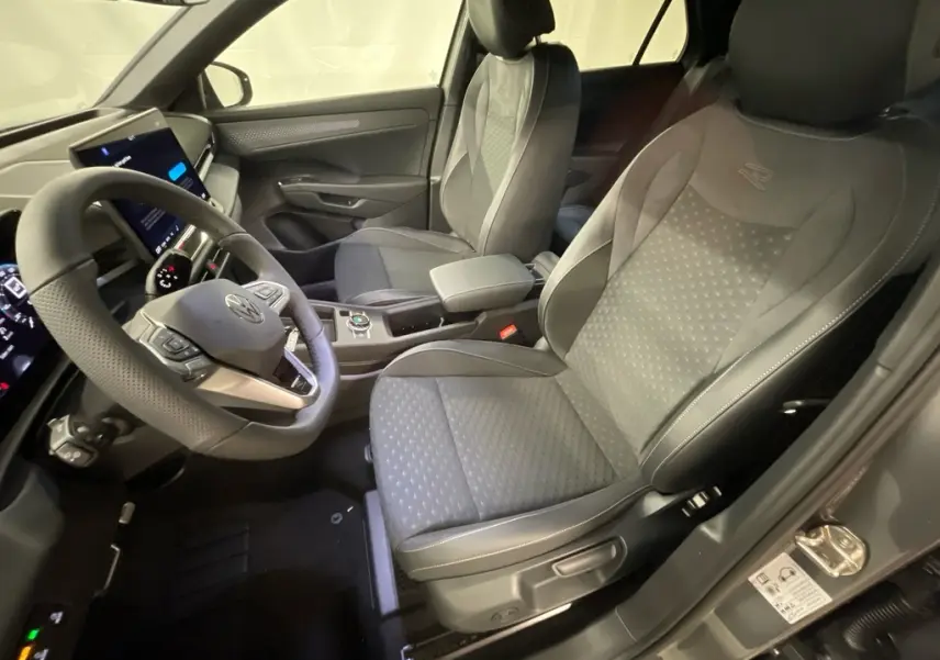 Vue intérieure côté conducteur du Volkswagen T-Roc gris Loup 2026, sièges sport R-Line et volant multifonction cuir.