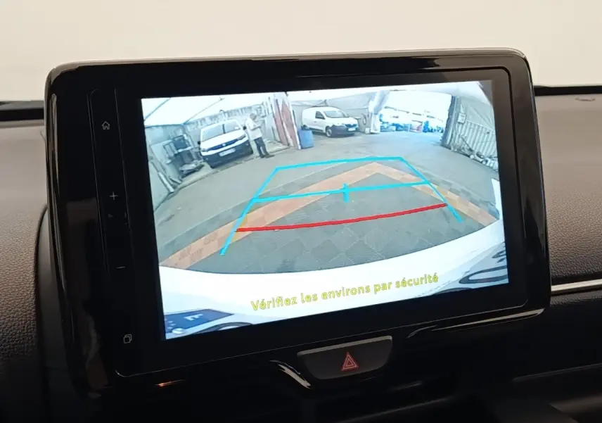 Écran tactile intérieur montrant la caméra de recul avec guidage coloré sur Toyota Yaris Hybride blanche.