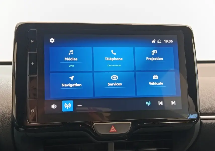 Tableau de bord avec écran tactile 9 pouces affichant menu médias, téléphone, navigation, et services sur Toyota Yaris Hybride blanche.