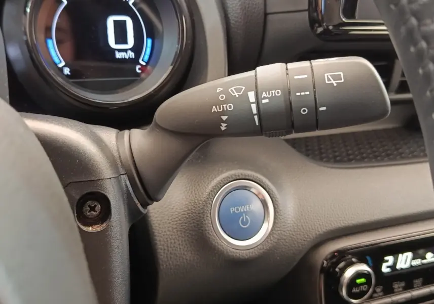 Gros plan intérieur sur le bouton Power bleu et la commande d’essuie-glace de la Toyota Yaris Hybride 2022.
