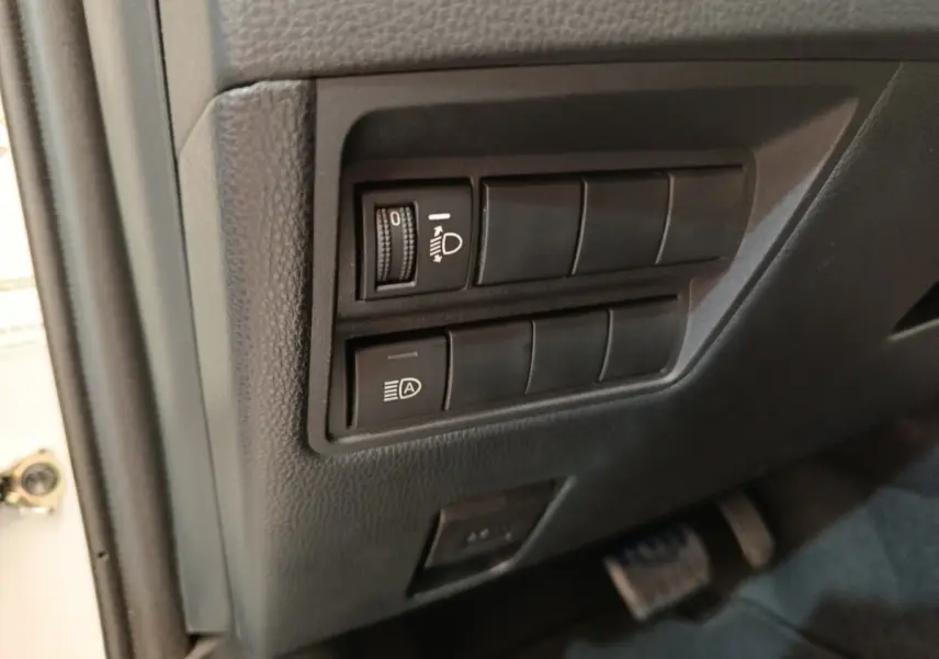 Détail des commandes d’éclairage sur le côté gauche du tableau de bord d’une Toyota Yaris hybride blanche 2022.