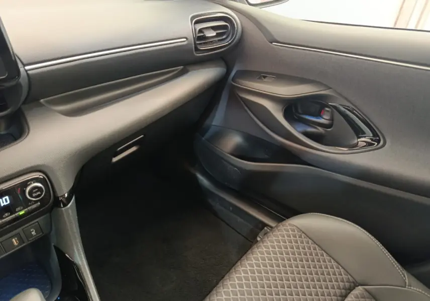 Vue intérieure côté passager avant de la Toyota Yaris Hybride 116h Collection 2022, avec tableau de bord et siège en cuir noir.