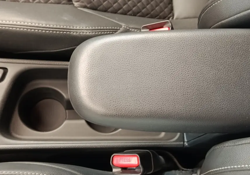 Gros plan sur l'accoudoir central noir et les ceintures de sécurité rouges de l'intérieur d'une Toyota Yaris Hybride 2022.