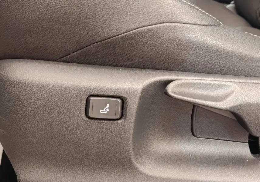 Détail du bouton de réglage lombaire sur le côté du siège avant en cuir gris foncé de la Toyota Yaris Hybride 116h Collection.