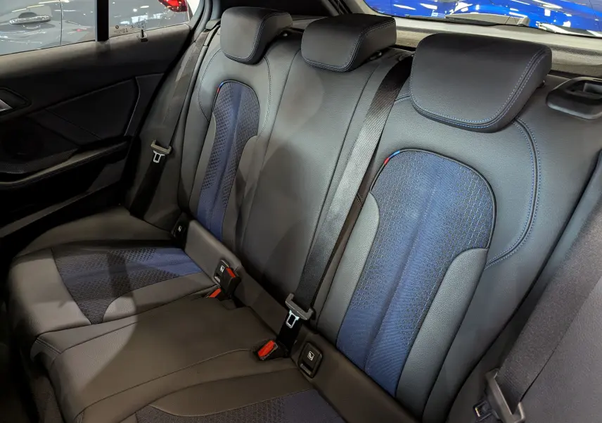 Vue intérieure des sièges arrière en cuir noir et tissu bleu avec surpiqûres bleues d'une BMW Série 1 F40 M Sport 2023.
