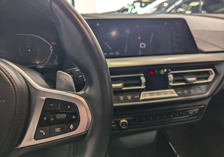 Vue rapprochée de l'intérieur côté conducteur de la BMW Série 1 F40, volant cuir noir et écran tactile central.