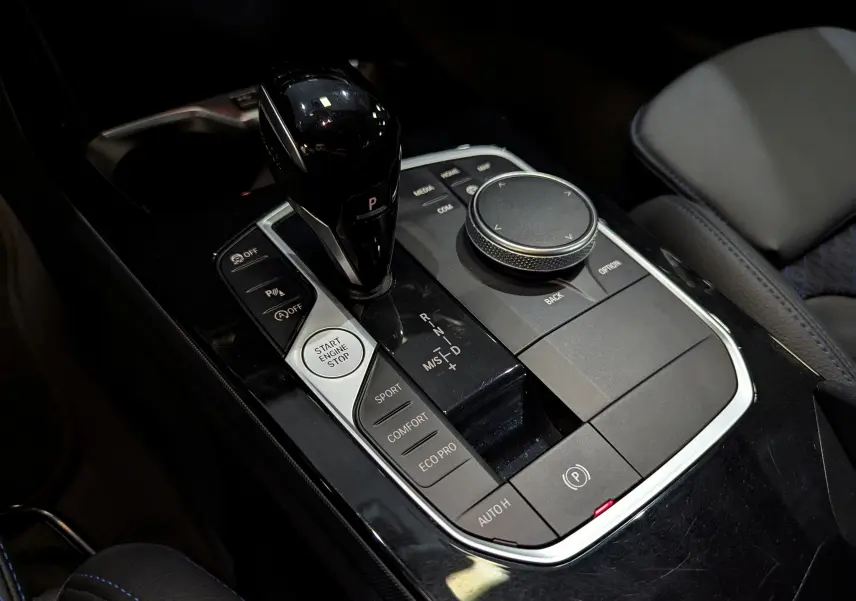 Gros plan sur la console centrale noire de la BMW Série 1 F40 18d avec levier de vitesse et commandes de conduite.