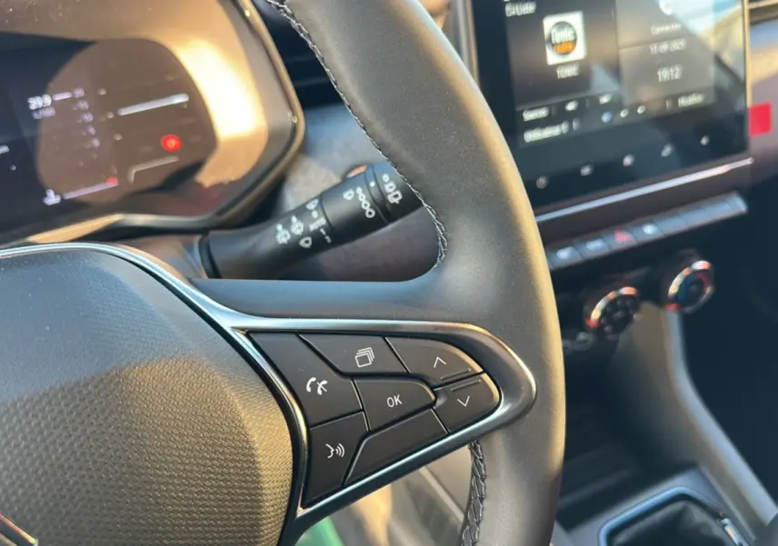 Gros plan sur le volant de la Renault Clio DCI 100 Evolution Camera 2025 avec commandes multifonctions et tableau de bord numérique.