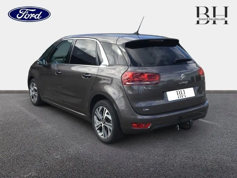 Vue 3/4 arrière droite d'une Citroën C4 Picasso gris Shark avec jantes alliage et vitres teintées.