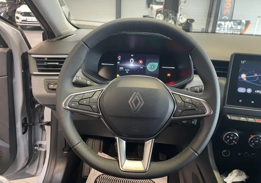 Vue intérieure centrée sur le volant noir de la Renault Clio 1.5 Blue dCi 2025 avec tableau de bord numérique et écran tactile.
