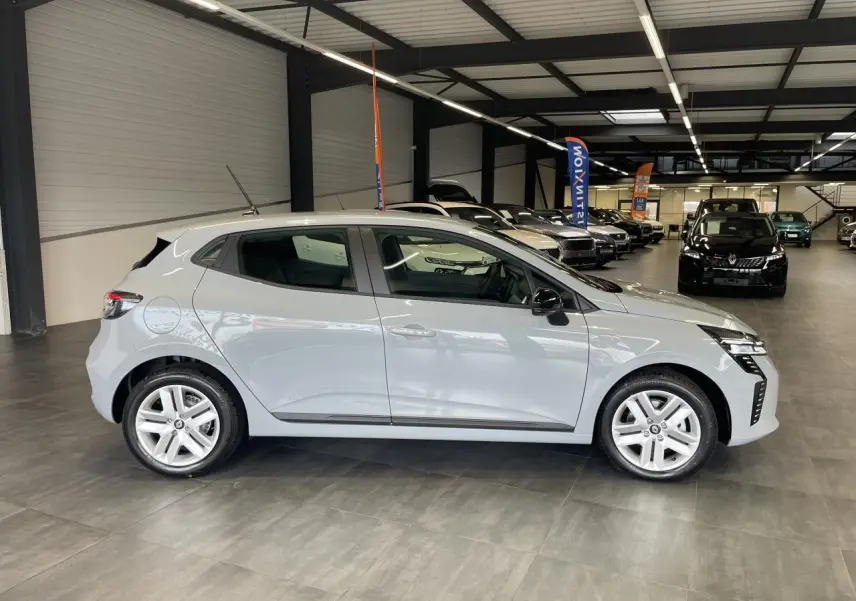 Profil côté gauche d'une Renault Clio 2025 gris Rafale avec jantes alliage et poignées couleur carrosserie en showroom.