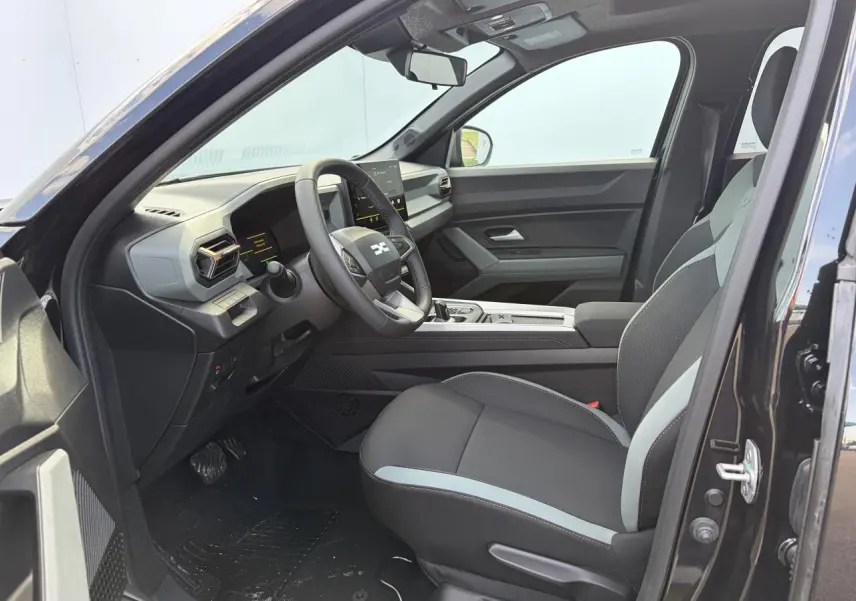 Vue intérieure côté conducteur du Dacia Bigster noir, mettant en valeur les sièges bi-ton et le tableau de bord moderne.