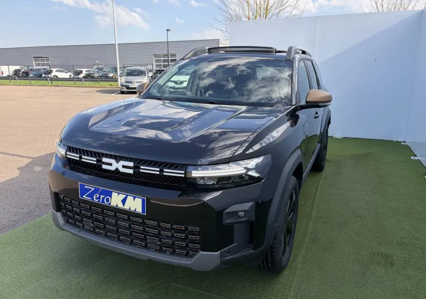 Vue 3/4 avant du Dacia Bigster noir nacré avec calandre et rétroviseurs brun cuivré, toit panoramique ouvert.