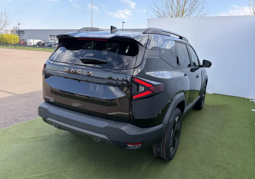 Vue 3/4 arrière droite du Dacia Bigster noir nacré avec feux arrière LED en forme de flèche et toit ouvrant panoramique.