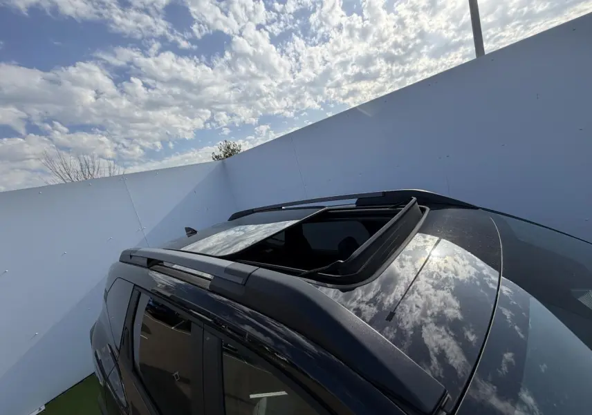 Toit ouvrant panoramique ouvert vu en plongée sur le côté gauche du Dacia Bigster noir nacré 2026.