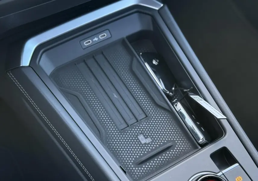 Vue rapprochée de la console centrale noire du Volkswagen T-Roc 2026 avec zone de charge sans fil et ports USB-C.