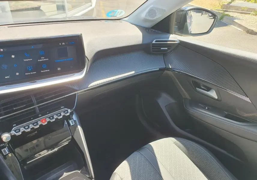 Vue intérieure côté passager de la Peugeot 208 1.2 Hybrid 110 Allure, avec tableau de bord noir et écran tactile 10 pouces.
