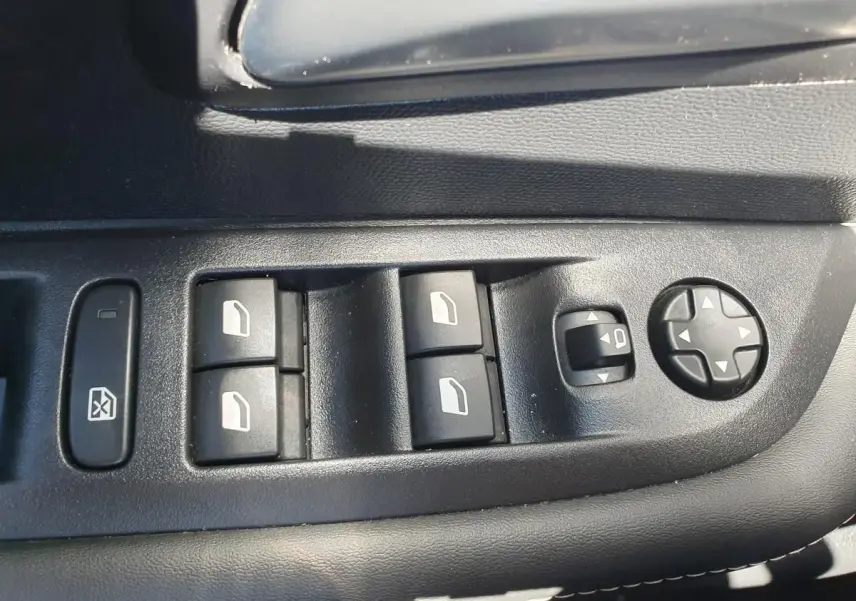Commande des vitres électriques et réglage des rétroviseurs sur la porte côté conducteur d'une Peugeot 208 gris Artense.