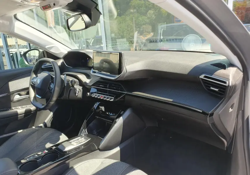 Intérieur avant droit de la Peugeot 208 1.2 Hybrid 110 gris Artense, avec tableau de bord moderne et écran tactile central.