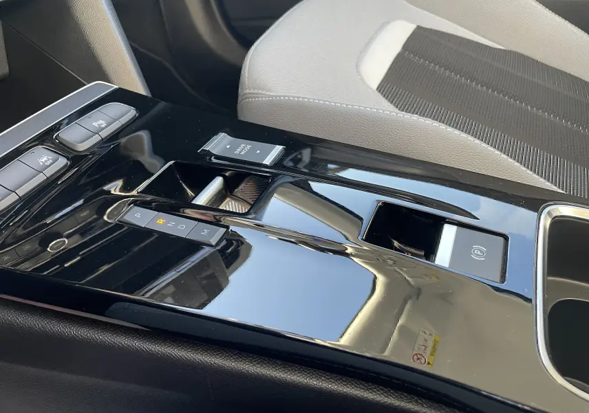 Gros plan sur la console centrale noire brillante de l’Opel Mokka 2023 avec levier de vitesse automatique et siège tissu gris.