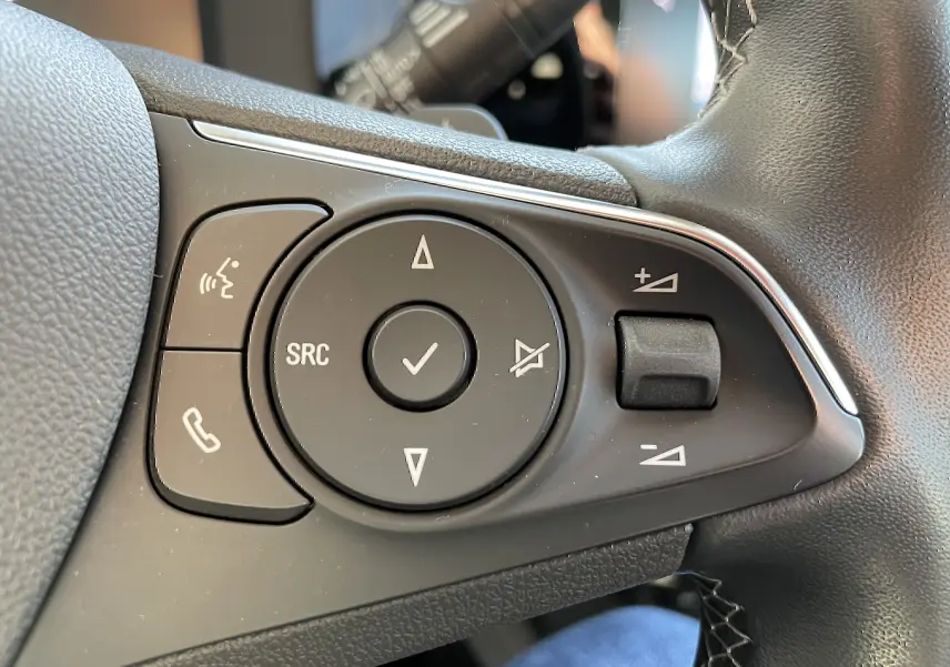 Gros plan sur les commandes du volant noir de l’Opel Mokka 2023, version Elegance Business.