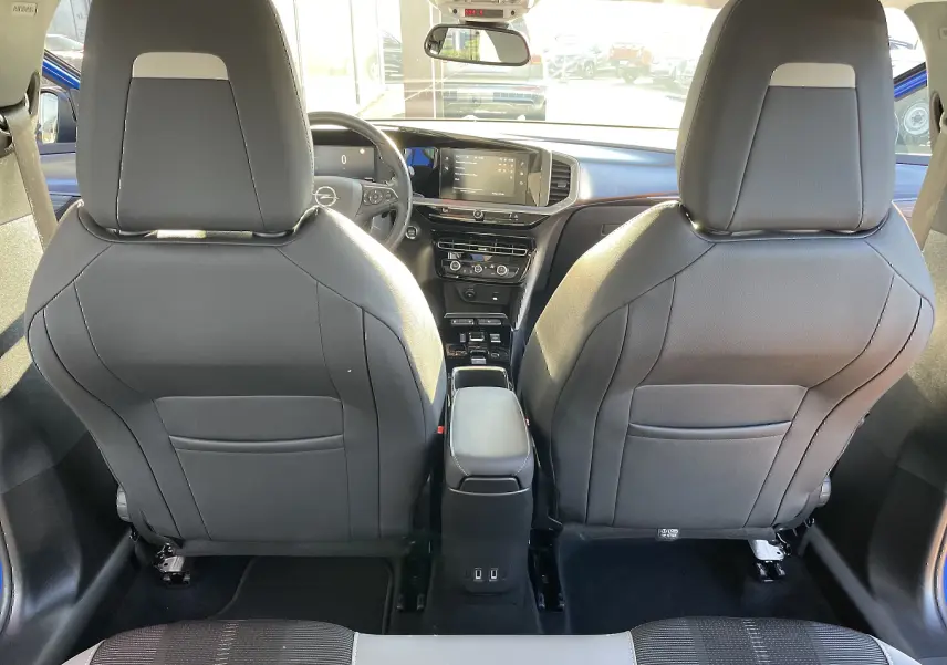 Vue intérieure arrière de l'Opel Mokka bleu Voltak 2023, montrant les sièges avant noirs et le tableau de bord moderne avec écran tactile.