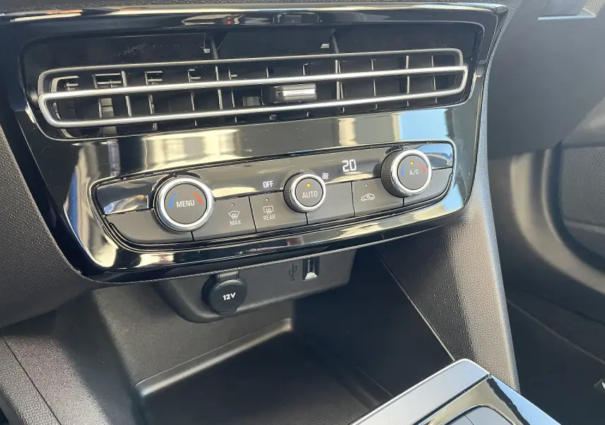 Gros plan sur la console centrale noire brillante de l’Opel Mokka 2023, montrant les commandes de climatisation automatique.