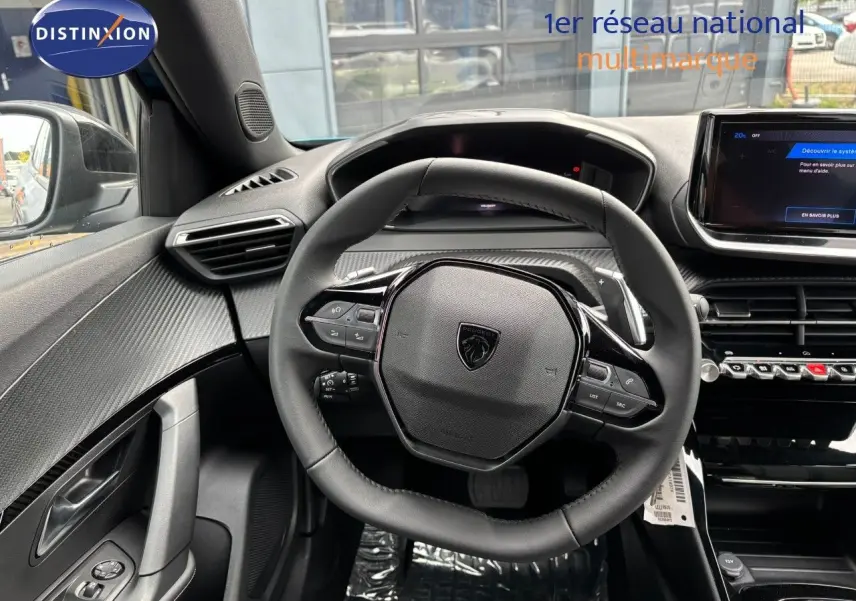 Vue rapprochée du volant cuir noir et tableau de bord moderne du Peugeot 2008 Hybrid 2025, ambiance intérieure soignée.