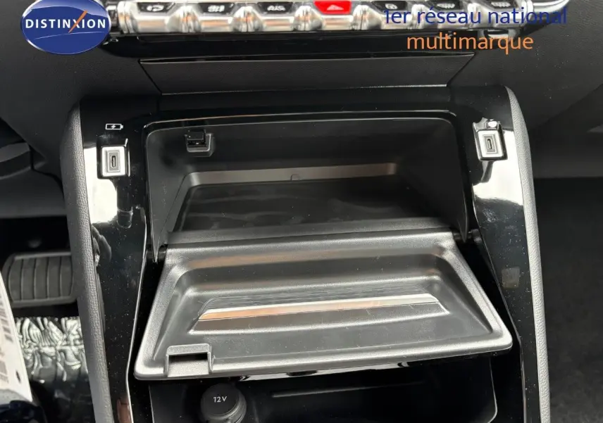 Vue rapprochée de la console centrale du Peugeot 2008 Hybrid 136ch Allure 2025, avec compartiment ouvert et prises USB visibles.