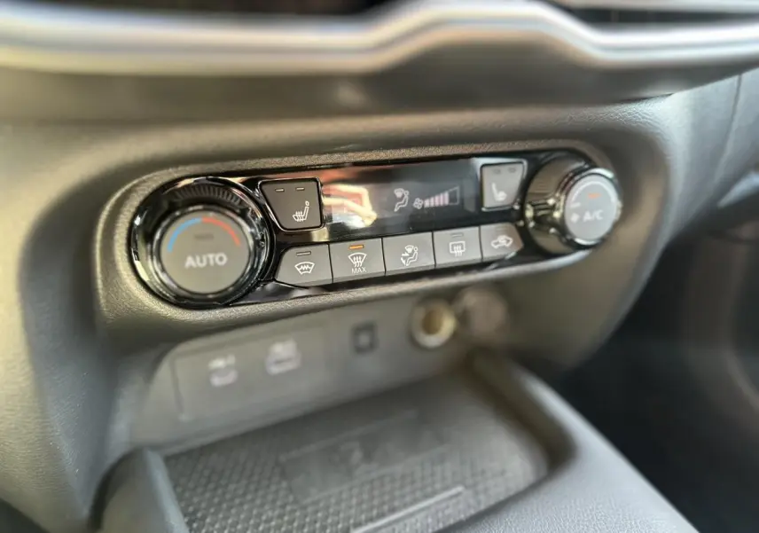Gros plan sur la console centrale noire du Nissan Juke 2025, mettant en valeur les commandes de climatisation et sièges chauffants.