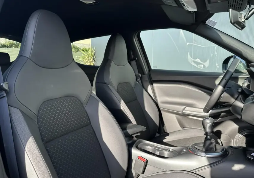 Intérieur du Nissan Juke 2025 noir, vue côté droit sur sièges avant en tissu et volant avec boîte manuelle.
