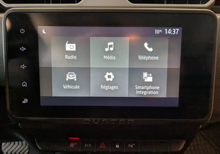 Écran tactile central du tableau de bord du Dacia Duster 2023 affichant les menus Radio, Média, Téléphone, Véhicule, Réglages et Smartphone Integration.