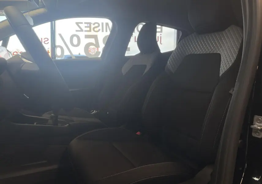 Vue intérieure côté gauche montrant les sièges avant tissu gris et noir de la Renault Clio 1.5 Blue dCi 2025.