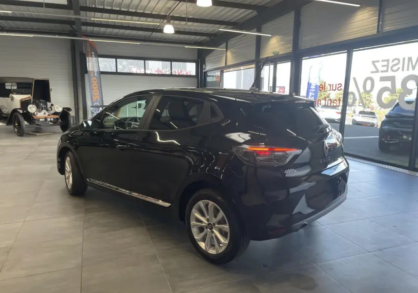 Renault Clio 2025 noir étoilé vue 3/4 arrière droit en intérieur avec jantes alu et feux LED allumés.