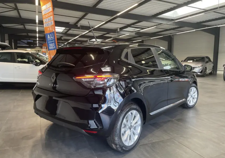 Renault Clio 2025 noir étoilé vue 3/4 arrière droit en intérieur avec jantes alu et feux LED allumés.