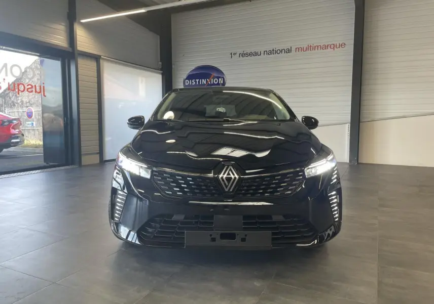 Vue de face d'une Renault Clio 1.5 Blue dCi 2025 en noir étoilé avec calandre et feux LED allumés dans un showroom.